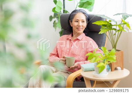 A woman sitting on a sofa and relaxing A woman sitting on a sofa and relaxing 129809175