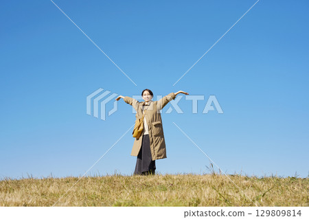 Woman, middle age, stretching, blue sky, whole body Woman, middle age, stretching, blue sky, whole body 129809814