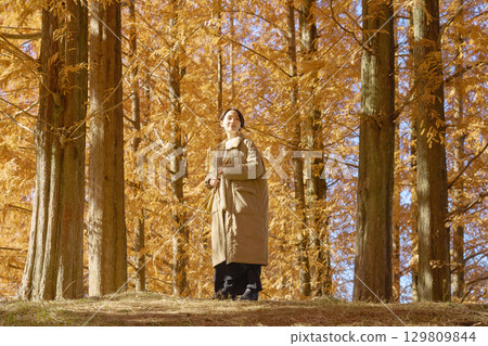 Middle-aged woman walking among autumn leaves Middle-aged woman walking among autumn leaves 129809844