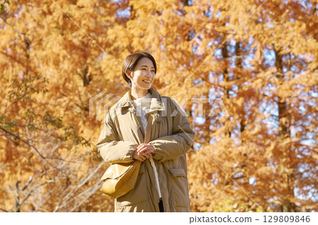 Middle-aged woman walking among autumn leaves 129809846