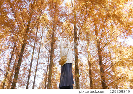 Middle-aged woman stretching among the autumn leaves Middle-aged woman stretching among the autumn leaves 129809849