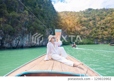 Happy Woman tourist in private longtail boat trip to koh Hong lagoon island at Krabi, Thailand. landmark, tropical destination, southeast Asia Travel, summer vacation, wanderlust and holiday concept Happy Woman tourist in private longtail boat trip to koh Hong lagoon island at Krabi, Thailand. landmark, tropical destination, southeast Asia Travel, summer vacation, wanderlust and holiday concept 129810902