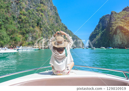 Woman tourist on boat trip, happy traveller relaxing at Pileh lagoon on Phi Phi island, Krabi, Thailand. Exotic landmark, destination Southeast Asia Travel, summer vacation and holiday concept Woman tourist on boat trip, happy traveller relaxing at Pileh lagoon on Phi Phi island, Krabi, Thailand. Exotic landmark, destination Southeast Asia Travel, summer vacation and holiday concept 129810919