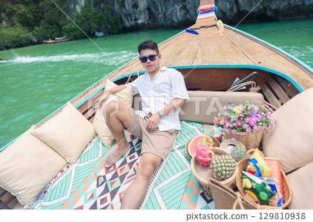 Happy man tourist in private longtail boat trip to koh Hong lagoon island at Krabi, Thailand. landmark, tropical destination, southeast Asia Travel, summer vacation, wanderlust and holiday concept Happy man tourist in private longtail boat trip to koh Hong lagoon island at Krabi, Thailand. landmark, tropical destination, southeast Asia Travel, summer vacation, wanderlust and holiday concept 129810938