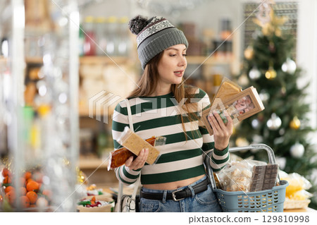 While shopping on eve of New Year holidays, young woman buys turron for festive party 129810998