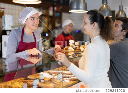 Bakery shop girl assistant talk to customer, answers questions and recommends fresh products Bakery shop girl assistant talk to customer, answers questions and recommends fresh products 129811020
