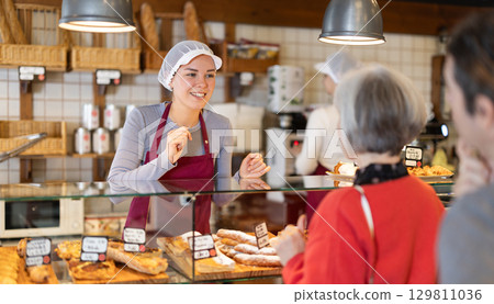 Saleswoman offers bakery customers to buy fresh baked goods Saleswoman offers bakery customers to buy fresh baked goods 129811036
