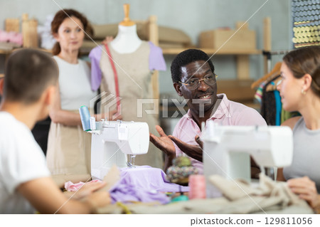 Participants in coterie practice sewing, chatting and talking, work with mannequin 129811056