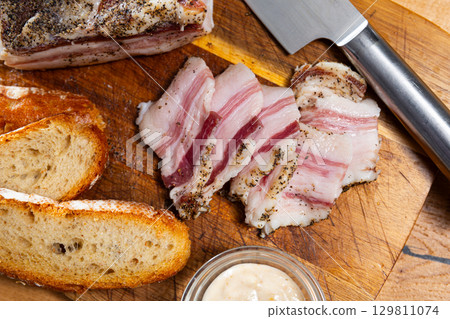 Sliced lard served with horseradish and bread 129811074