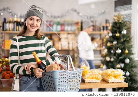Woman with grocery basket in supermarket 129811076