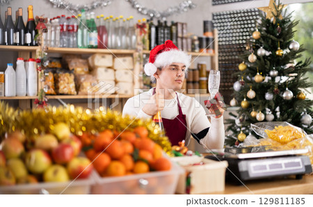 Bored salesman guy in deserted store sit with bottle of champagne and glass 129811185