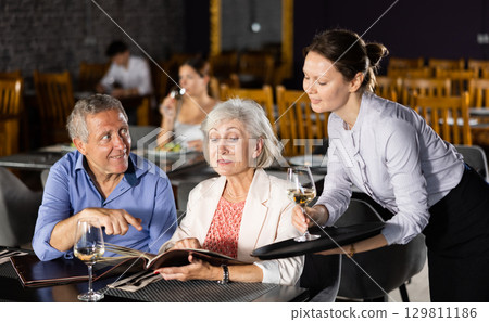 Woman waiter taking order from elderly couple in restaurant 129811186