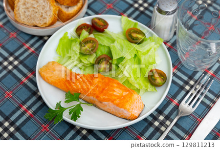 Delicious dish of seared salmon served with salad on side 129811213