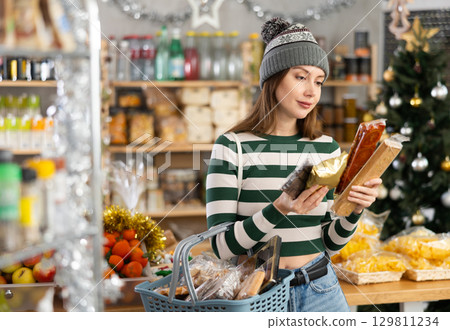 While shopping on eve of New Year holidays, young lady buys sweets for festive party 129811234