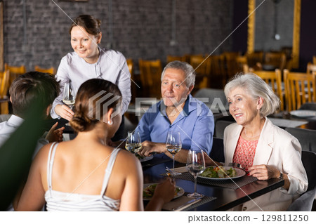 Elderly couple spending time with young friends in restaurant 129811250