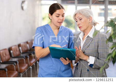Attentive female doctor prescribing tests to patient of clinic to check state of health 129811251