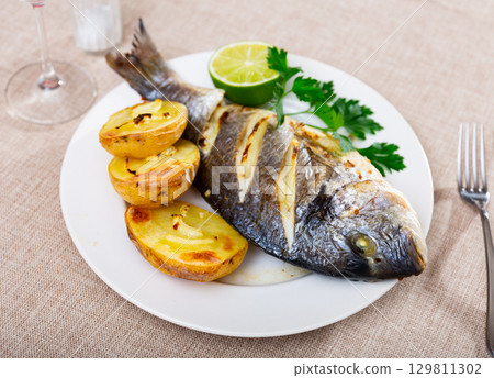 Fried dorada with baked jacket potato, lime and greens Fried dorada with baked jacket potato, lime and greens 129811302