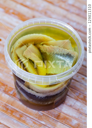 Marinated herring with onions and spice in plastic jar Marinated herring with onions and spice in plastic jar 129811310