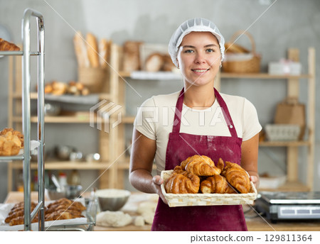 Young woman are standing in kitchen with basket of finished products croissant 129811364