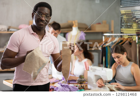 Positive middle-aged man holding textile detail fixed on paper 129811468