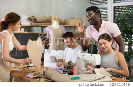 Teacher approving students progress in sewing class Teacher approving students progress in sewing class 129811496