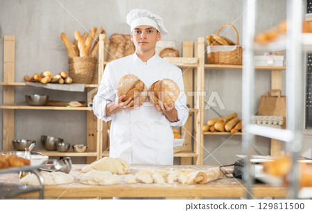 Bakery male employee holds ready made bread of bread in hands 129811500