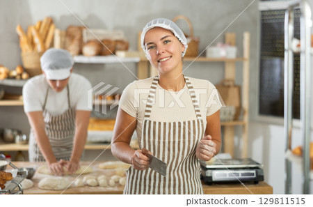 Young female baker holding a dough cutter in bakery 129811515