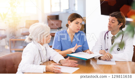 Young female physician discussing diagnosis of patients with colleagues Young female physician discussing diagnosis of patients with colleagues 129811638