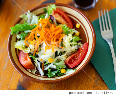 Plate contains portion of salad from fresh China cabbage, carrot, corn Plate contains portion of salad from fresh China cabbage, carrot, corn 129811679