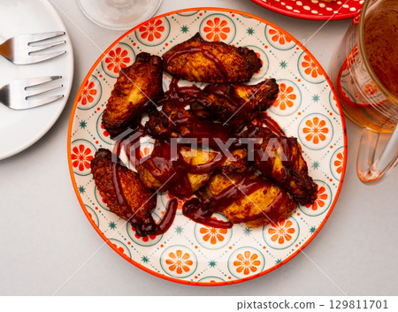 Delicious fried chicken wings with golden crust in sauce bbq on plate. Spanish appetizer - alitas en salsa BBQ 129811701