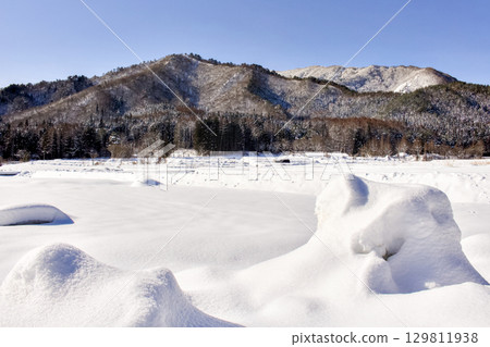 The view of the mountains beyond the snow-covered fields is beautiful. 129811938