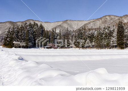 The view of the mountains beyond the snow-covered fields is beautiful. 129811939