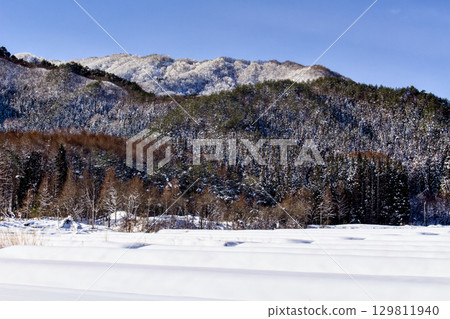 The view of the mountains beyond the snow-covered fields is beautiful. 129811940