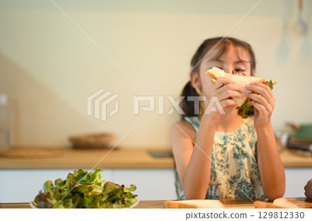 Cute little girl preparing to eat a fresh sandwich, representing healthy food and family lifestyle 129812330