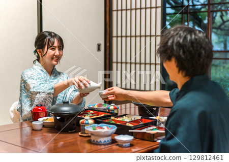 身穿浴衣的年輕亞洲女性在日式旅館晚餐時提供飲料,一對夫婦,一對夫妻 身穿浴衣的年輕亞洲女性在日式旅館晚餐時提供飲料,一對夫婦,一對夫妻 129812461