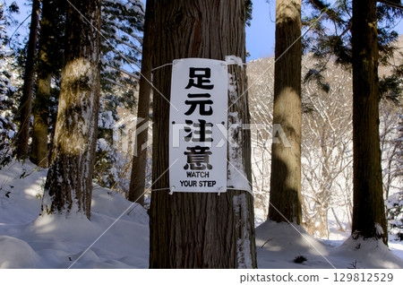 A sign on a snowy mountain saying "Watch your step" 129812529