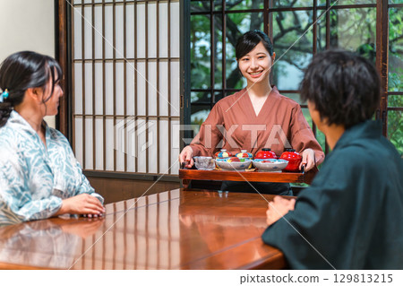 A female inn staff member serving food at a Japanese inn or Kappo restaurant, a waitress or landlady A female inn staff member serving food at a Japanese inn or Kappo restaurant, a waitress or landlady 129813215
