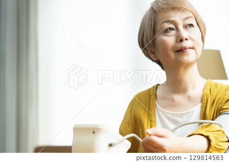 一位老年婦女在客廳測量血壓 129814563