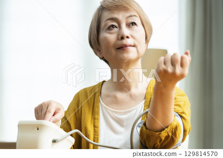 一位老年婦女在客廳測量血壓 129814570