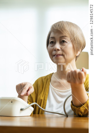 一位老年婦女在客廳測量血壓 129814572