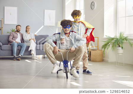 Happy playful family, parents and excited funny little brothers at home wearing super hero fancy  129814652