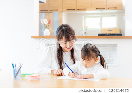 Daughter studying with her mother 129814675