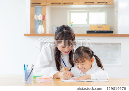 Daughter studying with her mother Daughter studying with her mother 129814676