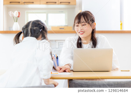 一個女孩在客廳學習,她的母親在遠距工作 一個女孩在客廳學習,她的母親在遠距工作 129814684