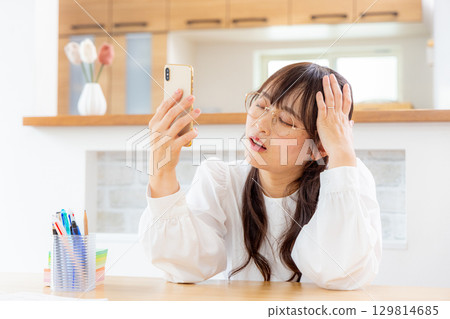 A woman troubled while watching a smartphone A woman troubled while watching a smartphone 129814685