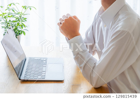 一位商人在筆記型電腦前思考的圖片 129815439