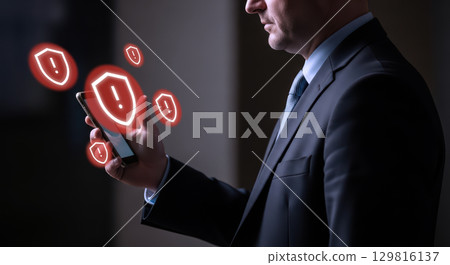 Mobile cybersecurity threat alert with red warning shield on smartphone screen showing security breach 129816137