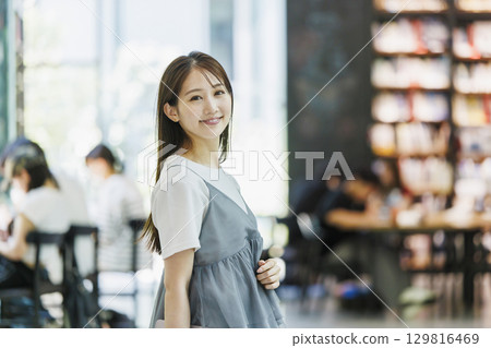 站在圖書館裡的年輕女子 129816469