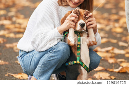 Covering the eyes with paws. Young woman is with her dog in the park Covering the eyes with paws. Young woman is with her dog in the park 129816725
