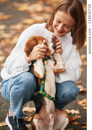 Covering the eyes with paws. Young woman is with her dog in the park Covering the eyes with paws. Young woman is with her dog in the park 129816726